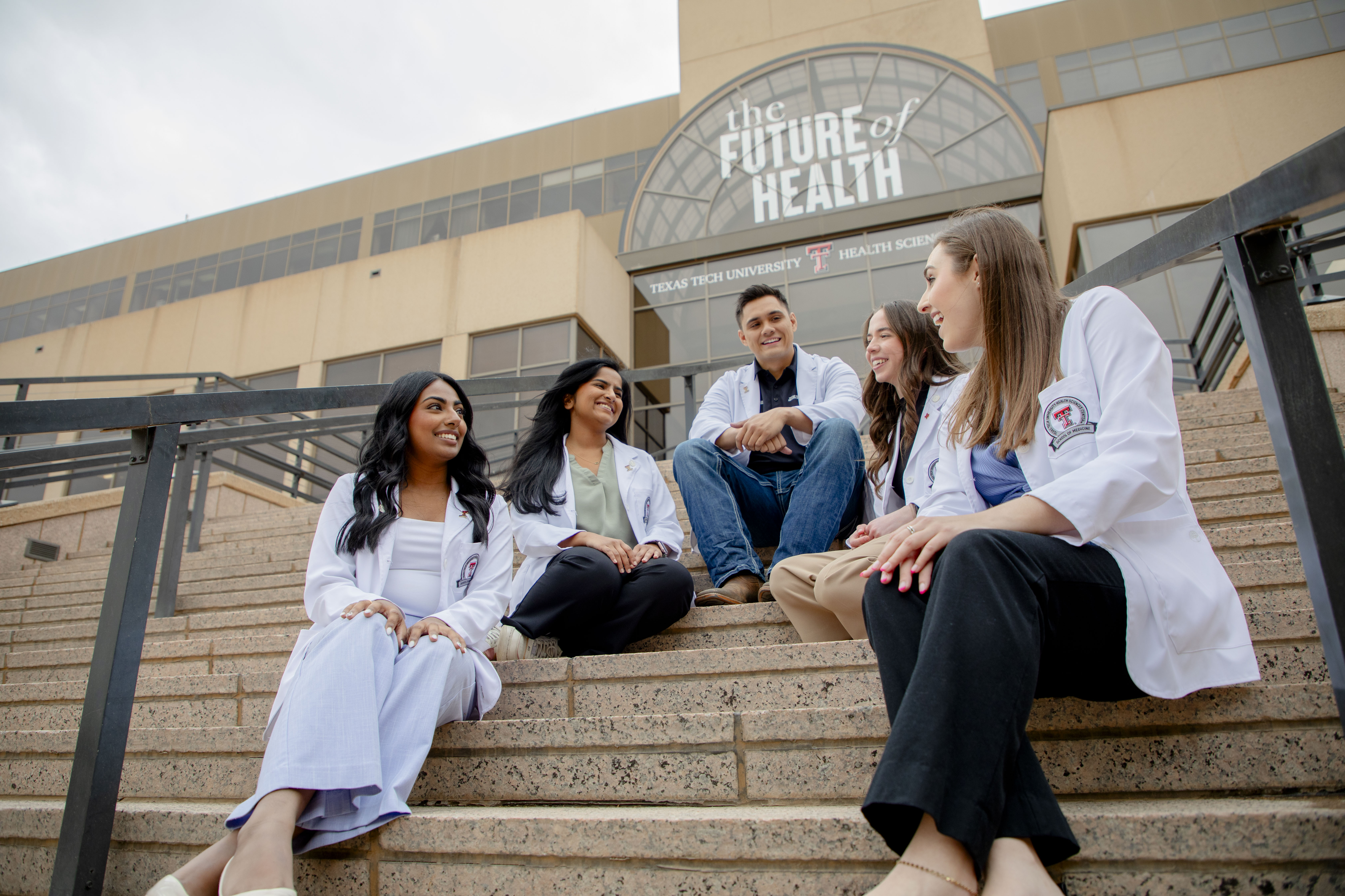 five medical students sitting and talking on a stairwell of TTUHSC