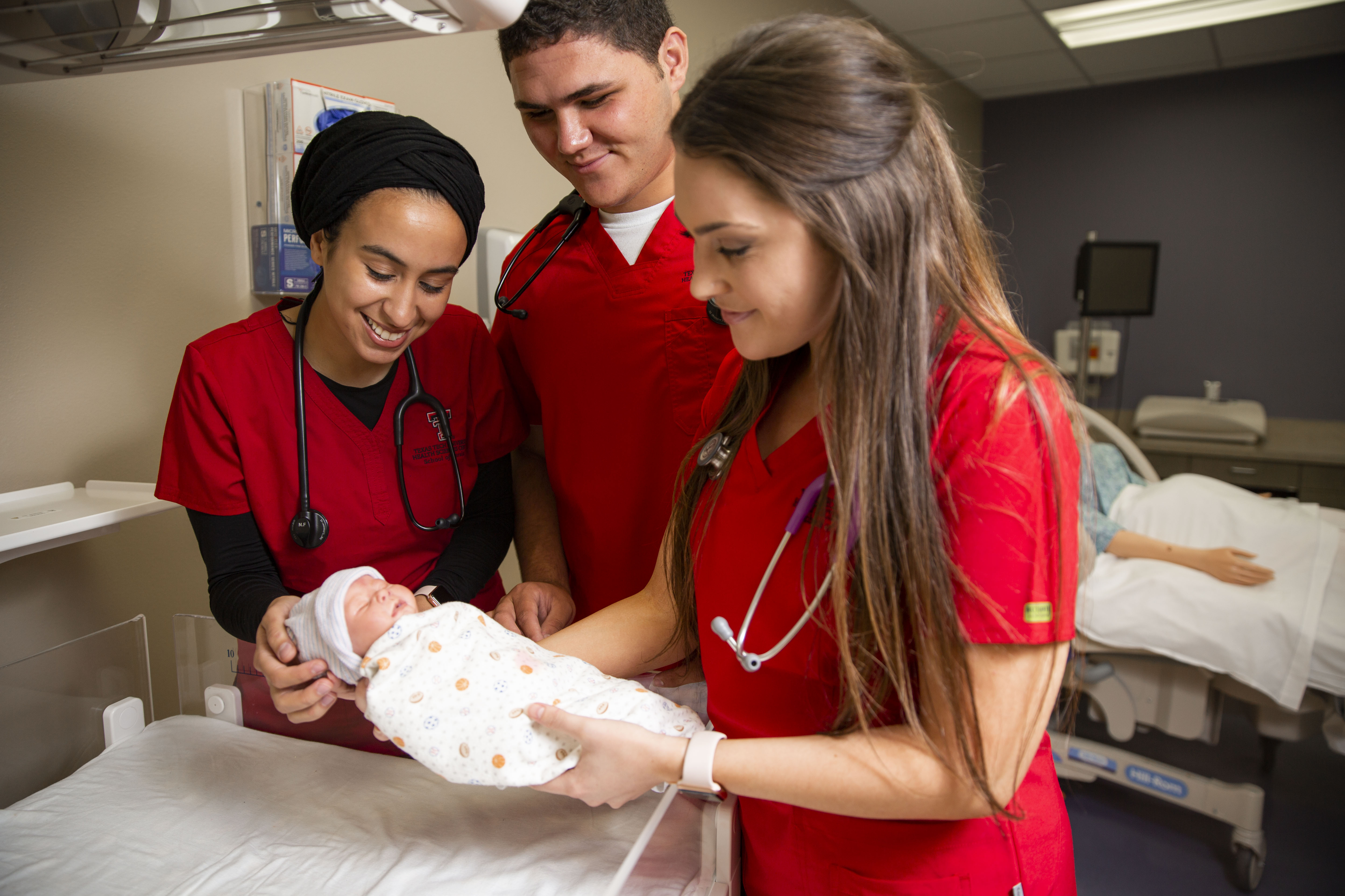 Nursing students holding infant in simulation lab